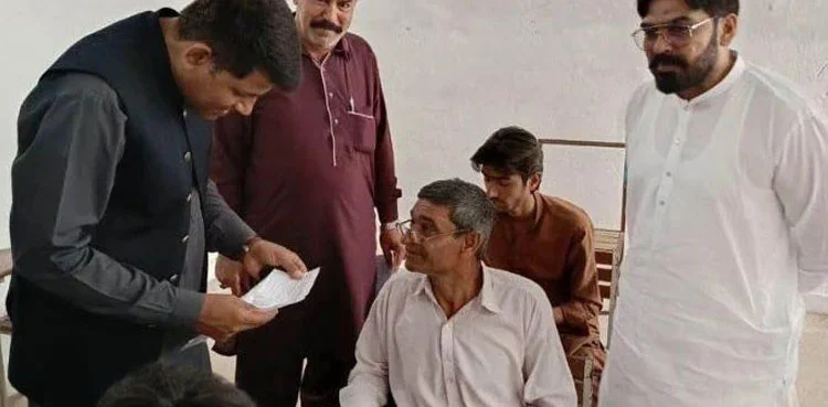 55-year-old student sitting in exam hall with staff checking documents