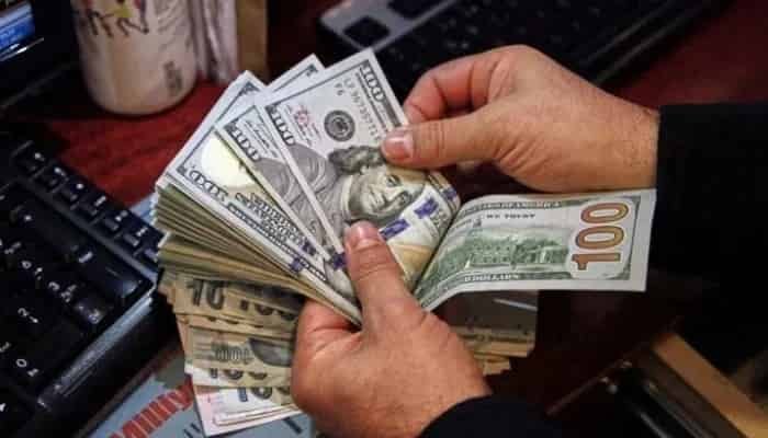 Money changer counting US dollars after Pakistan UAE deposit repayment