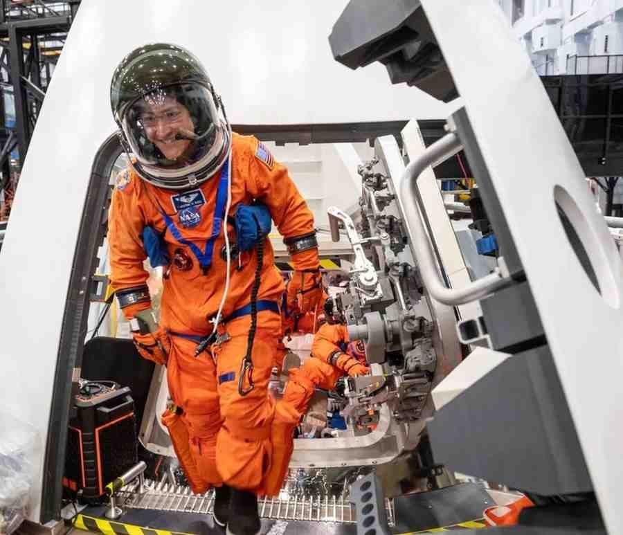 Astronaut in orange NASA suit inside Orion spacecraft during training