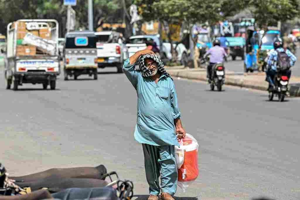 Man walking on Karachi road during extreme heatwave carrying water cooler