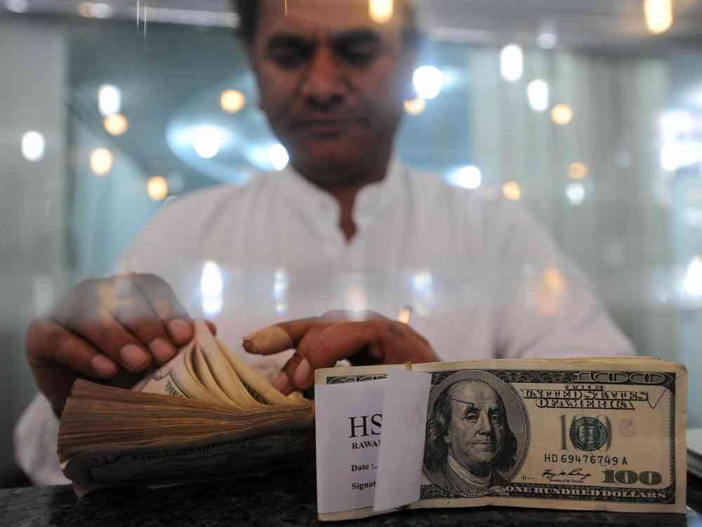 Pakistani currency exchange worker counting US dollars for overseas remittance transfer