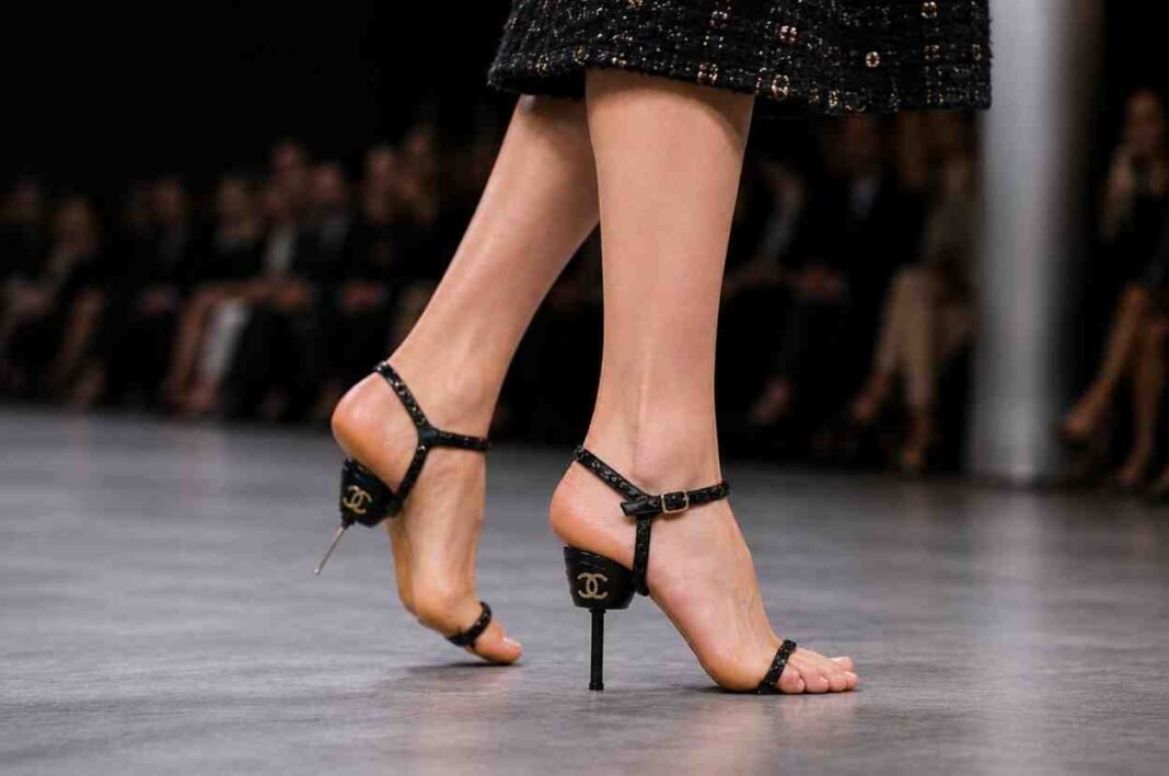 Model wearing black soleless sandals during luxury fashion runway show