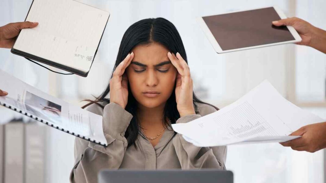 Stressed employee overwhelmed with work pressure showing toxic workplace signs in office