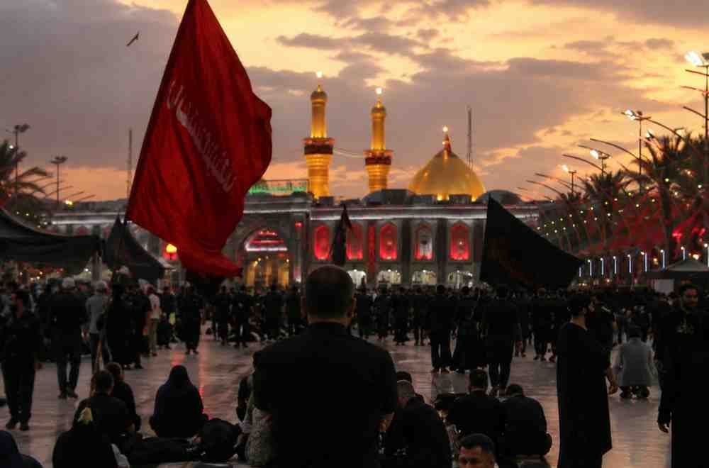 Muharram mourners gather at a shrine during a solemn evening procession.