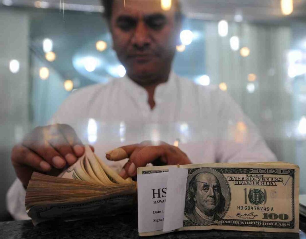 A currency exchange worker counts US dollar notes at a remittance center in Pakistan.