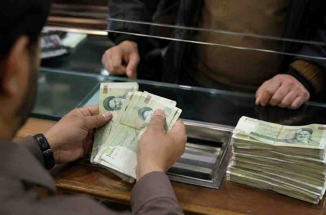 Customer counts Iranian rial notes at a currency exchange counter.