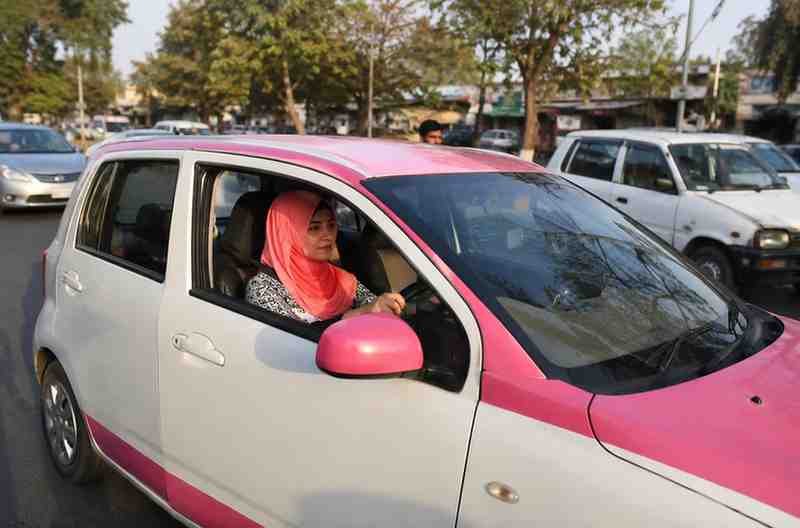 Woman driving a pink taxi on a busy Sindh city road.