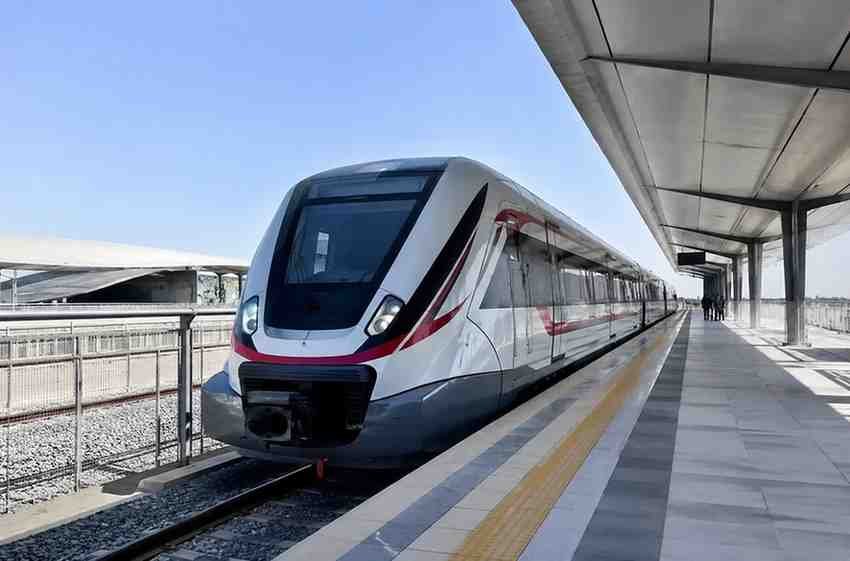UAE passenger train standing at a modern station platform in daylight.