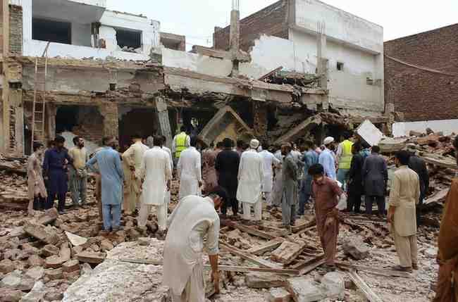People inspect a damaged school building after a roof collapse incident.