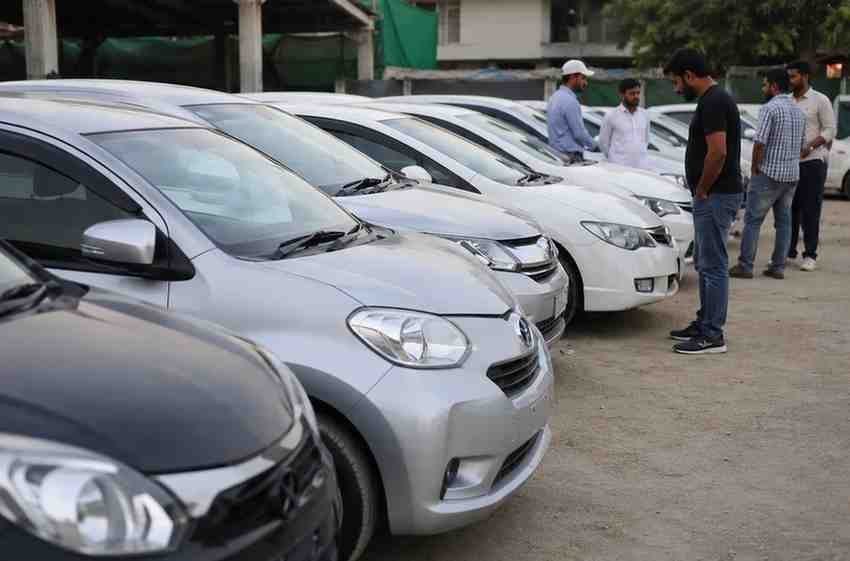 Buyers inspect imported used cars at an outdoor car market.