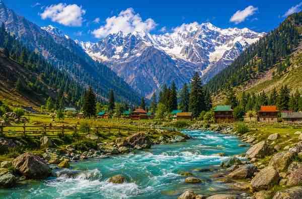 Scenic mountain valley with a crystal-clear river and snow-capped peaks in northern Pakistan.