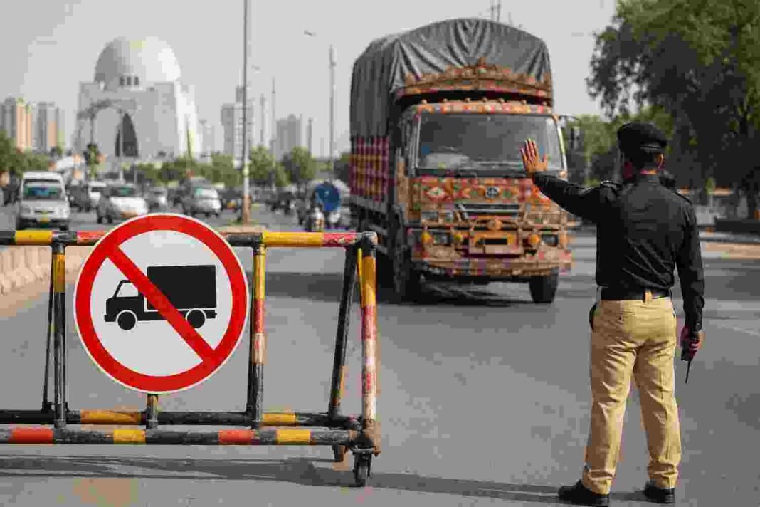 Heavy Vehicle Entry Ban on August 25–26 Karachi traffic police officer stopping a heavy truck during city entry restrictions.