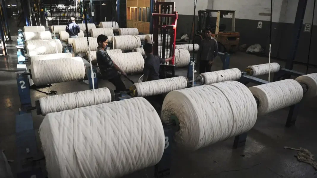Zahidjee Textile Mills Shuts 262-Loom Weaving Unit Amid Industry Pressure Workers handle yarn rolls on a textile factory floor in Pakistan; Zahidjee Textile Mills has shut its 262-loom weaving unit