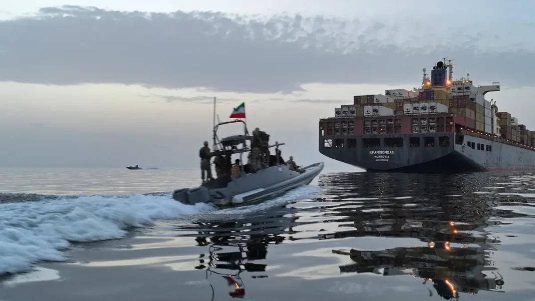 Iran’s Guards Say Supertanker Exploded After Hitting Mine in Strait of Hormuz An Iranian patrol boat passes a merchant vessel near the Strait of Hormuz after the Hormuz supertanker mine explosion