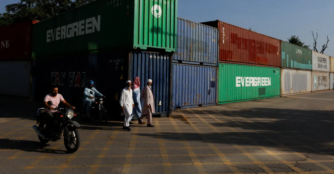 Containers pile up at Karachi port as trucks are seized to block Islamabad ahead of PTI’s October 4 march Men walk past shipping containers used as a blockade in Islamabad before the PTI march; containers seized for PTI march blockades