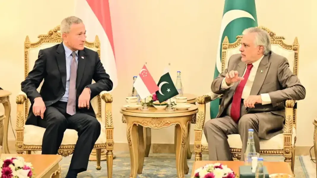 Dar, Singapore FM Exchange Disaster Management MoU Ishaq Dar and Vivian Balakrishnan seated with Pakistan and Singapore flags - Pakistan Singapore disaster management MoU