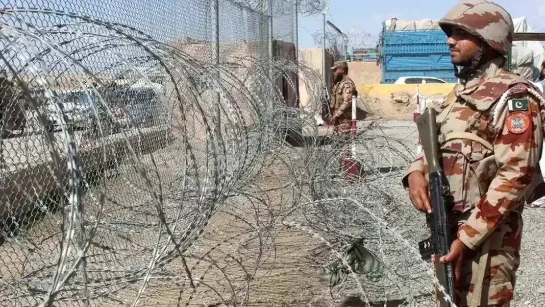 Army Response at Angoor Adda After Border Firing A Pakistani soldier stands guard at a border fence with barbed wire, Angoor Adda