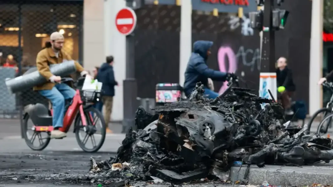 France Counts Cost of Violent Cost-of-Living Protests as 1,800 Arrested Burnt-out vehicle wreckage on a Paris street after the cost-of-living protests in France